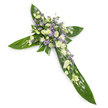 A solemn, carefully crafted floral cross laid on a clean white backdrop, captured from a slight overhead angle so every element reads clearly. Broad, glossy tropical leaves - the kind often called Ti leaves - form the green skeletal frame of the cross: layered, veined, and waxy to the touch, they create bold horizontal and vertical arms that feel both protective and natural. At the central intersection and trailing softly along each arm, clusters of soft white and creamy ivory blooms are densely arranged to draw the eye inward. Ruffled lisianthus with their layered, delicate petals and closed buds give a whisper-soft texture, while small white, daisy-like chrysanthemums add bright points and gentle contrast. Interspersed among these are sprays of powdery lavender to pale purple tiny flowers - limonium or small asters - that offer a quiet, cooling accent and a sense of depth. Fine green filler foliage threads through the clusters, softening edges and adding an airy, organic finish. Even in stillness the composition suggests scent: a faint, green freshness with the barely-there perfume of lisianthus and the clean, green lift of tropical leaves. The even, soft light eliminates harsh shadows and gives the arrangement a serene, almost liturgical calm, appropriate for funeral chapels, memorial services, or a graveside gathering. For families around Beckton and the Royal Docks, this cross reads as a dignified symbol of faith and remembrance - a comforting floral tribute that speaks of peace, continuity, and the quiet dignity of nature in mourning.