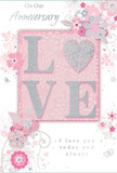 This anniversary card is designed as a gentle celebration of enduring romance, as if chosen from a display near a fresh flower stand in Beckton. The focal point is the word LOVE, elegantly set in raised, soft glitter, with each letter outlined in shimmering silver that adds a refined sparkle without overpowering the design. The letter O is transformed into a radiant heart, its textured silver surface standing out like a piece of jewellery nestled among petals. Surrounding this central word, delicate blooms in blush pink and muted mauve unfurl with a soft, watercolor-like quality, their edges slightly diffused as though painted with the lightest touch of a brush. Fine, flowing lines describe each petal and leaf, curling gently around the lettering in graceful arcs that echo the curves of a romantic bouquet arranged for delivery across Beckton's neighbourhoods. Tiny details-scattered petals, subtle swirls, and small, almost secret butterflies-add a sense of movement and whimsy, recalling the charm of an English spring garden in Newham. The colour palette blends pastel pinks with silvery greys, creating a feeling of treasured intimacy, like the soft light that filters through curtains on a quiet anniversary morning. Alongside the artwork, the words On Our Anniversary and I love you today and always appear in an understated, scripted font, expressing warmth without excess. The overall composition feels like a keepsake: refined, romantic, and thoughtfully crafted, mirroring the care that goes into choosing anniversary flowers for someone cherished in the Beckton area.